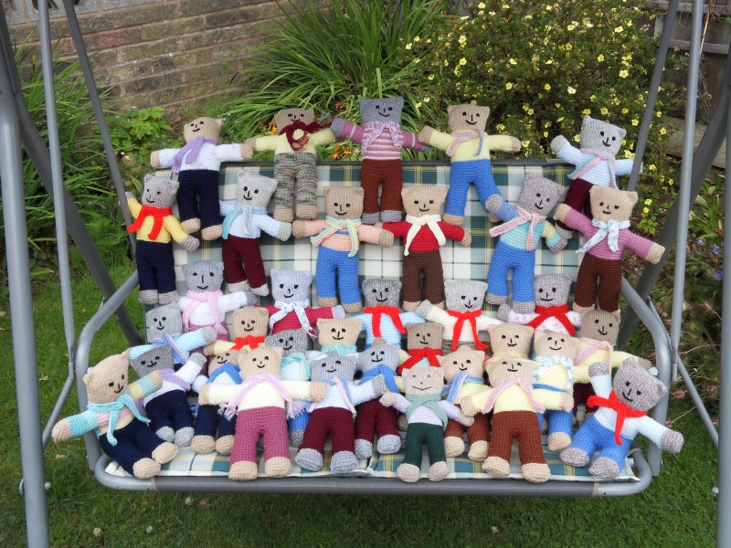 Knitted teddy bears on a swing in the garden