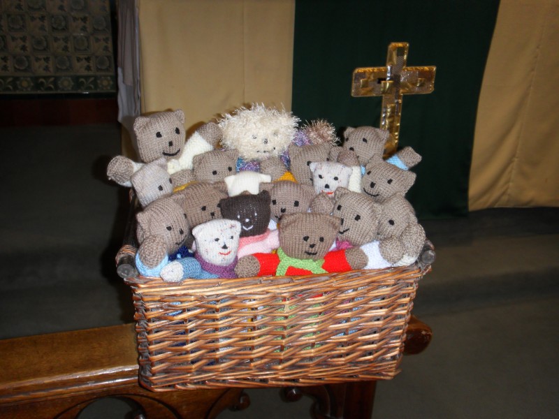 Knitted teddy bears in a basket in front of an altar cross